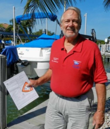 Man on dock holding clipboard and VSC sticker, with boat in background